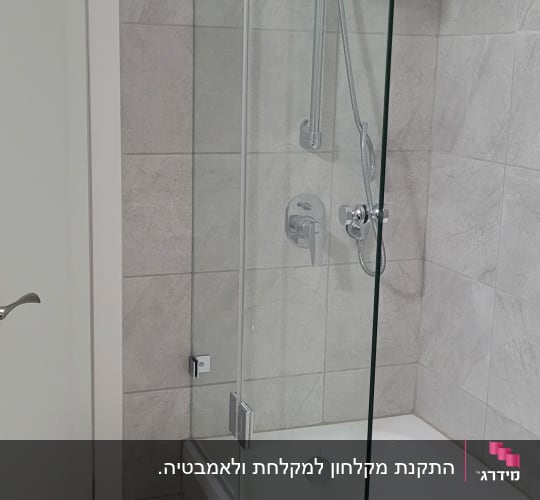 מקלחון זכוכית באמבטיה עם אריחים אפורים